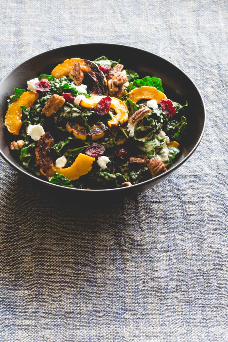 Photo of a kale salad with feta, sweet potato, dried cranberries, and walnuts.