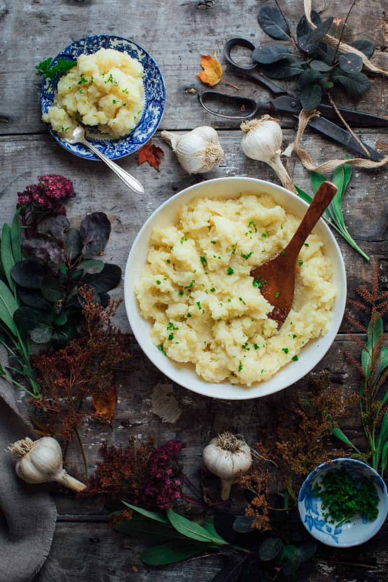 Healthy garlic mashed potatoes in a serving bowl and a smaller bowl of mash alongside.