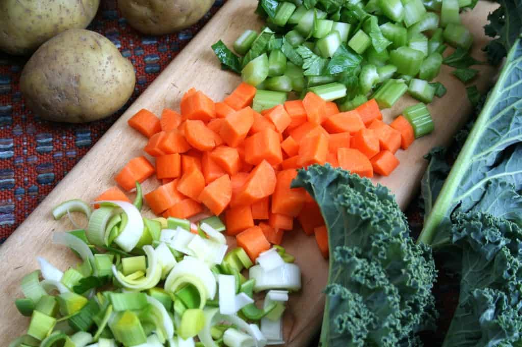 ingredients on a board: leeks, celery, carrots, potatoes and kale