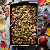 a table with autumn leaves and a casserole dish of stuffing