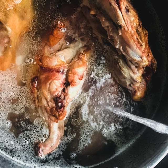 chicken bones in a pot with water pouring over them