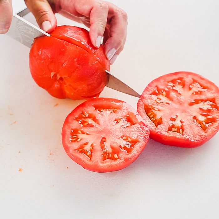 Cut the tomatoes in half along the equator to reveal the seed chambers.