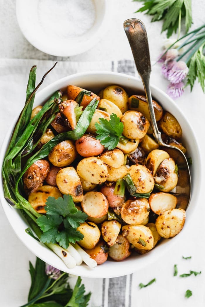 Overhead view of bowl of grilled potatoes with grilled scallions
