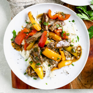 pepper steak in circular white dish over a bed of rice