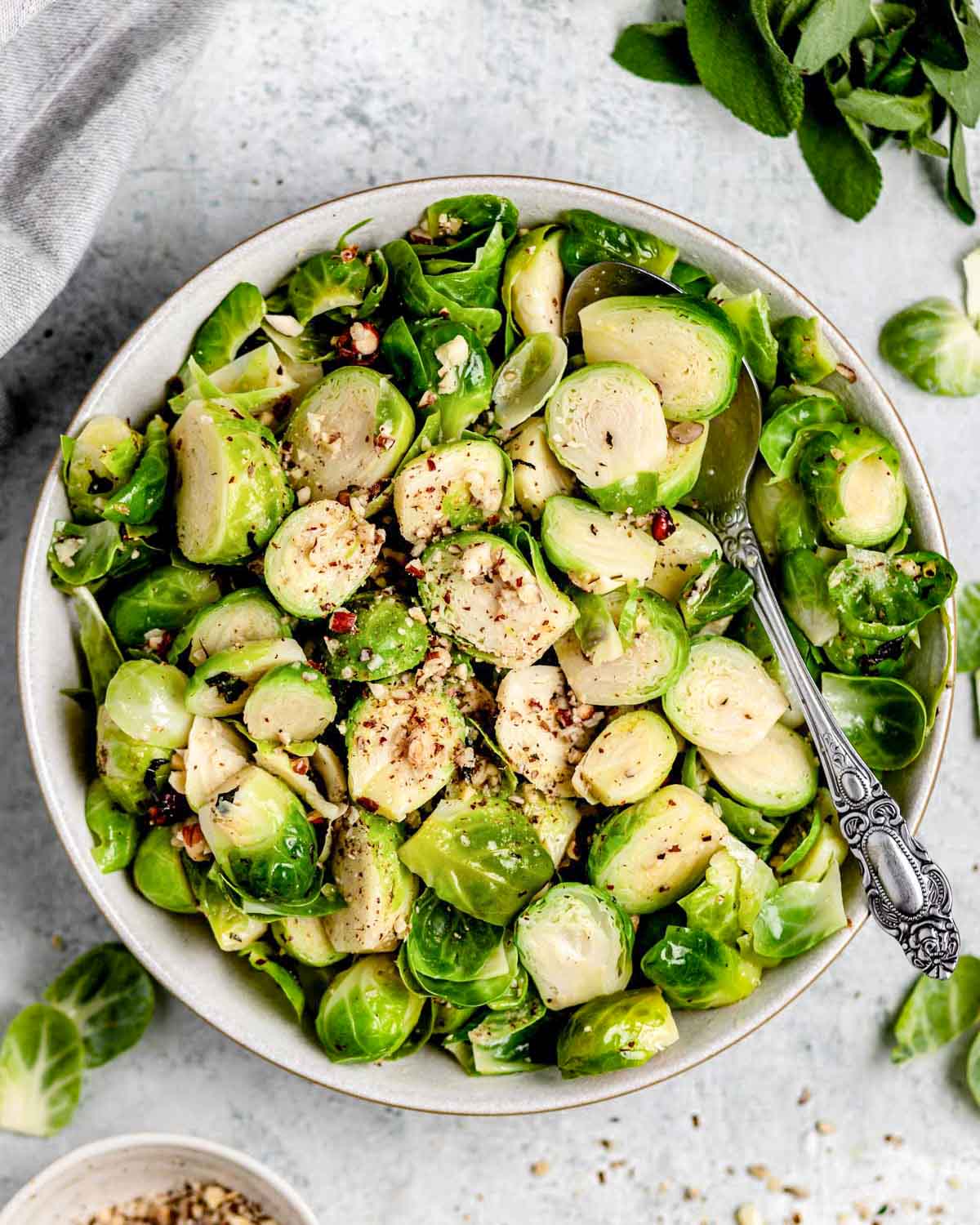 brussels sprouts with hazelnuts and sage in a white bowl with a spoon