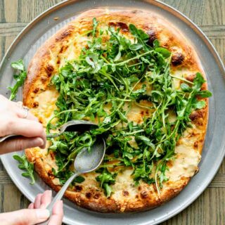 topping the pizza with the arugula salad
