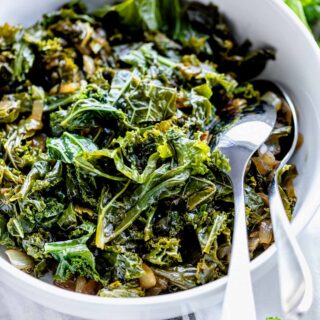 close up of sauteed kale in white circular bowl with serving wear
