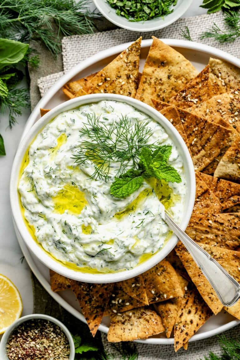 a closeup of the tzatziki with mint and dill garnish