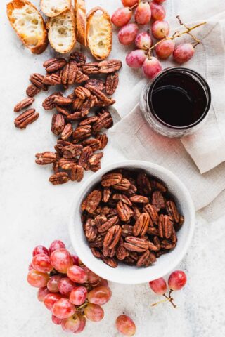 a white table with spiced pecans spilled out over it