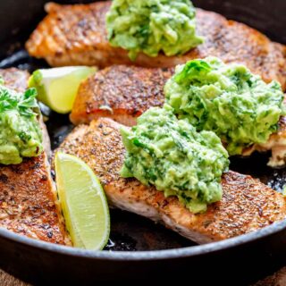 close up of the salmon in the skillet with the avocado on top