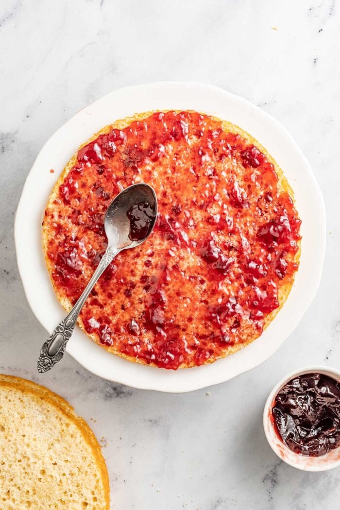 Spreading raspberry jam between each cake layer