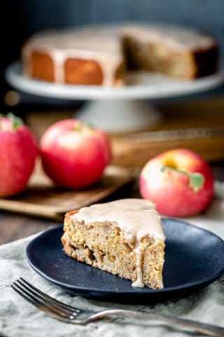 Apple cake slice with maple icing drizzling down the side