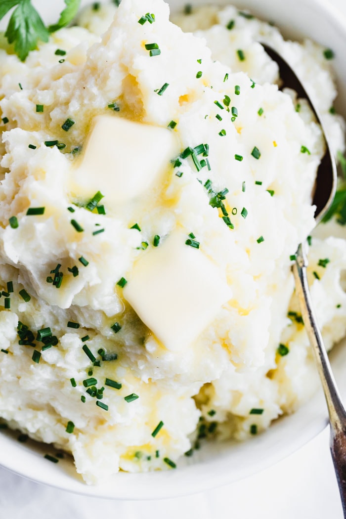 A close up of a bowl of buttermilk mashed potatoes with chives on top