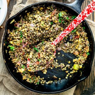 lentils in a skillet with a red and white speckled spoon