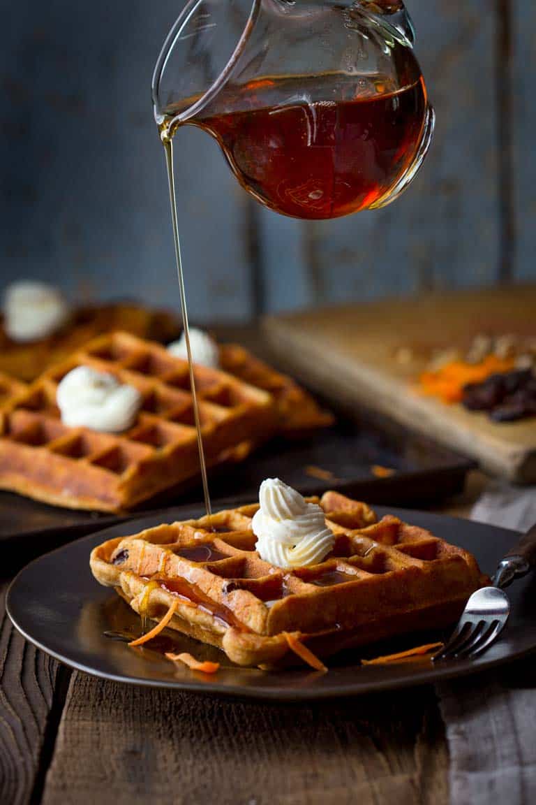 pouring maple syrup over Carrot Cake Waffles