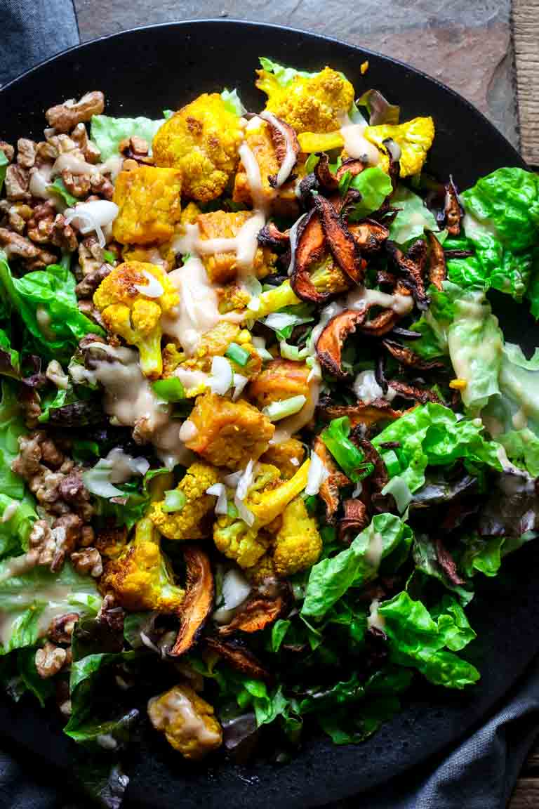 lettuce topped with vegan bacon, turmeric roasted cauliflower, and tempeh