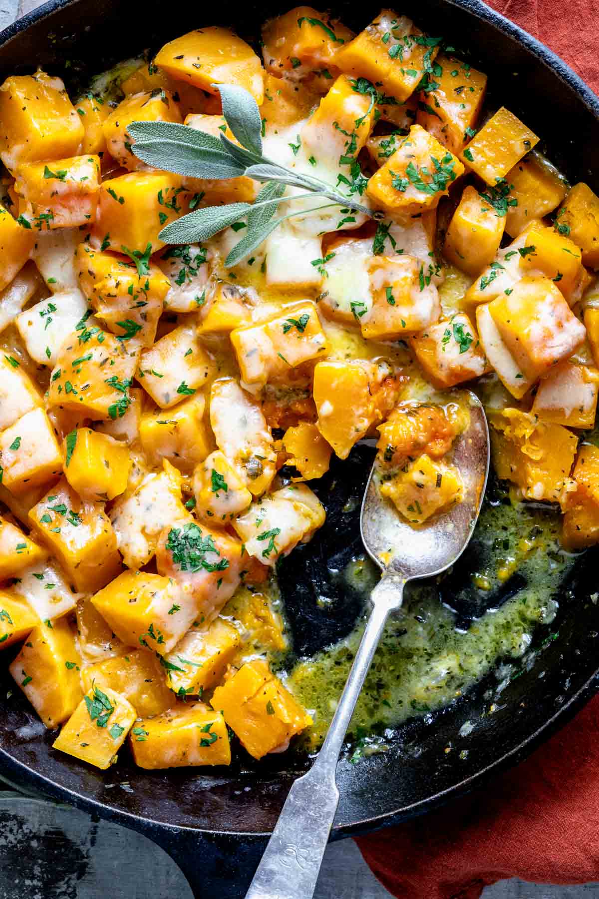 Easy cheesy butternut squash in a cast iron pan with a spoon