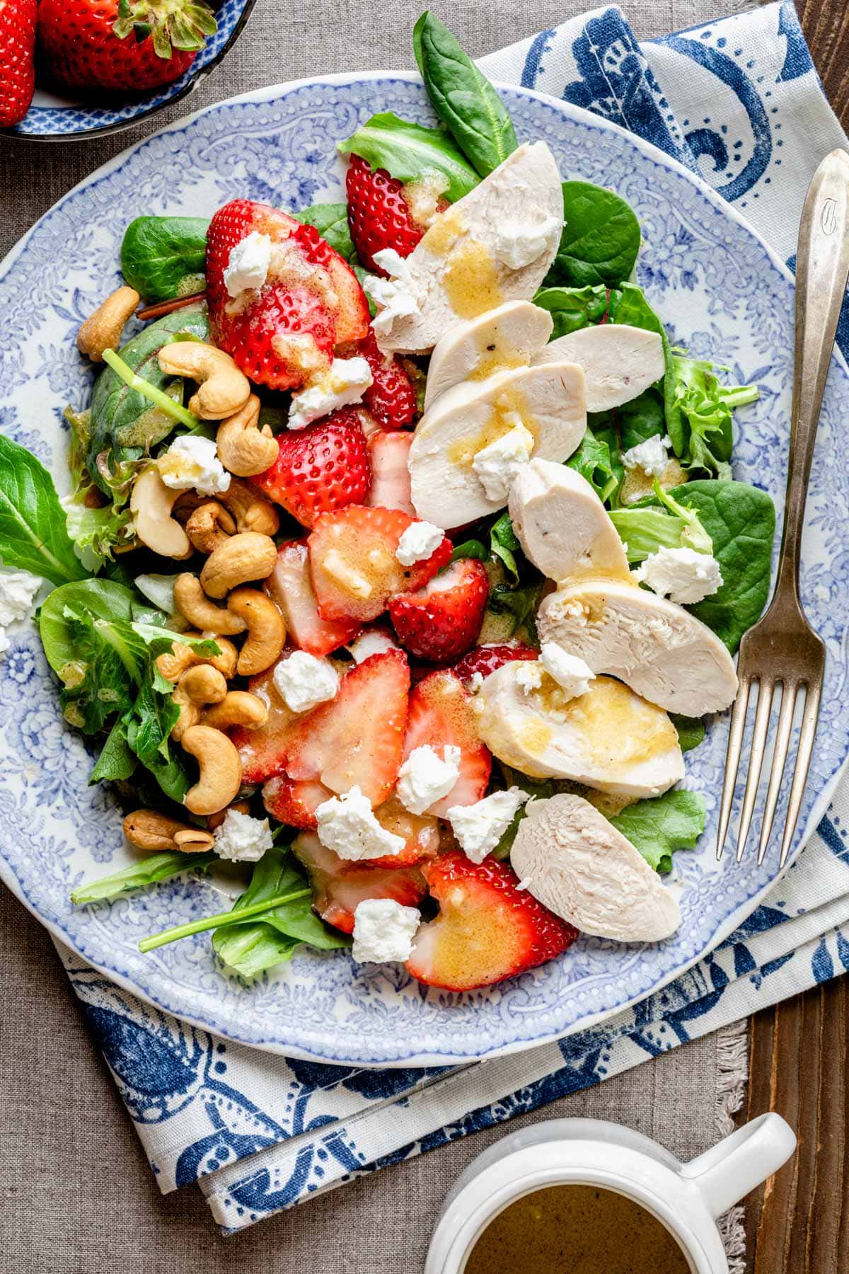 a blue and white plate with the salad on it, in a composed rows with dressing drizzled over it