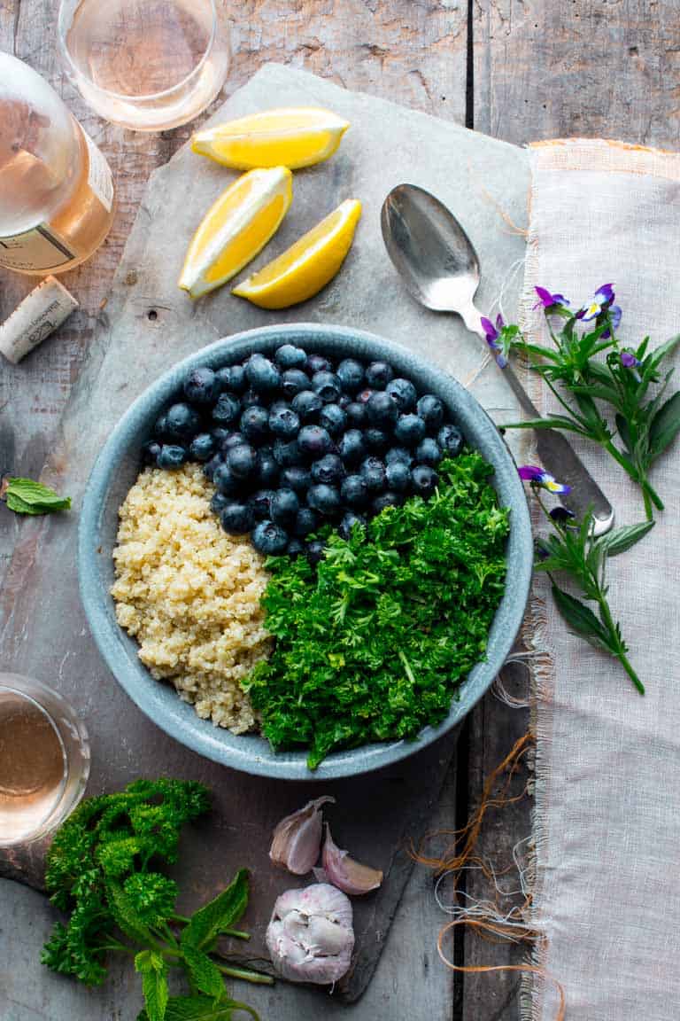 an overhead view of the ingredients in a bowl for quinoa blueberry tabbouleh
