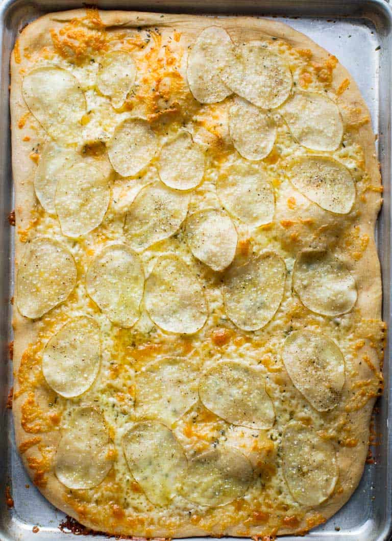 Have you heard of potato pizza before? If not, keep an open mind, and prepare your taste buds for a surprisingly delicious combination. In this white pizza version, I have a bit of rosemary, garlic and cheddar cheese to make it super savory and yummy! #vegetarian #pizza #whitepizza #potato #cheddar