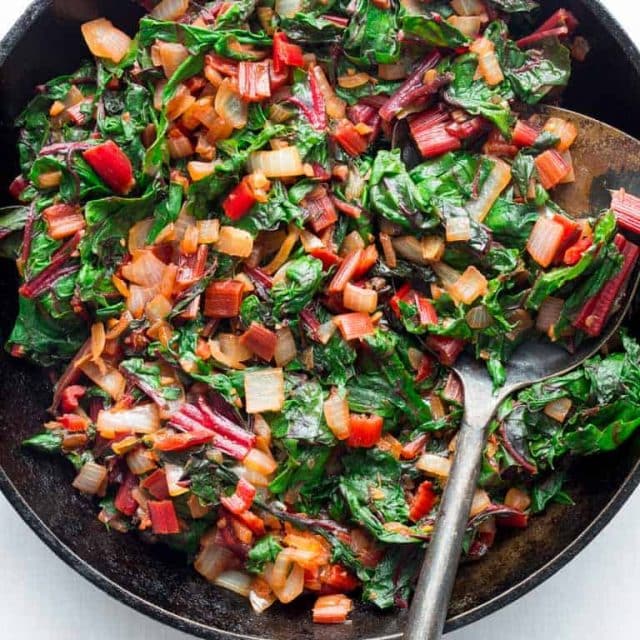 A black skillet with sautéed swiss chard, overhead