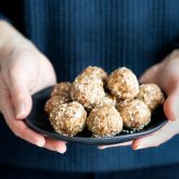 hands holding a plate of paleo energy balls