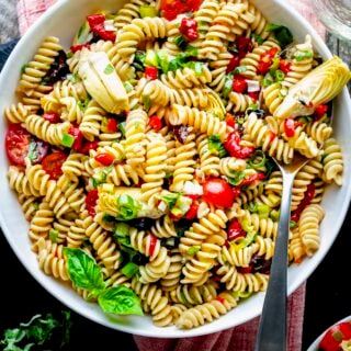 the pasta salad in a white bowl from overhead with a stainless steel serving spoon in it