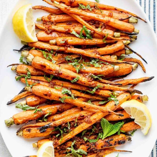 white platter of grilled carrots on a blue and white tablecloth