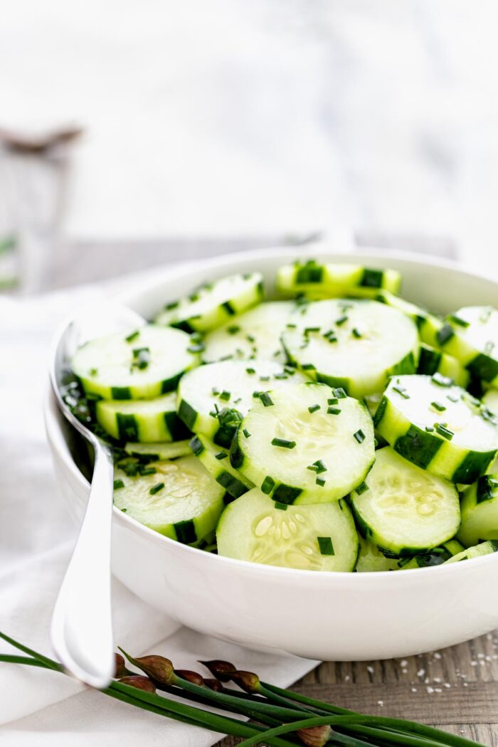 cucumber salad in a white bowl from the side with backlighting
