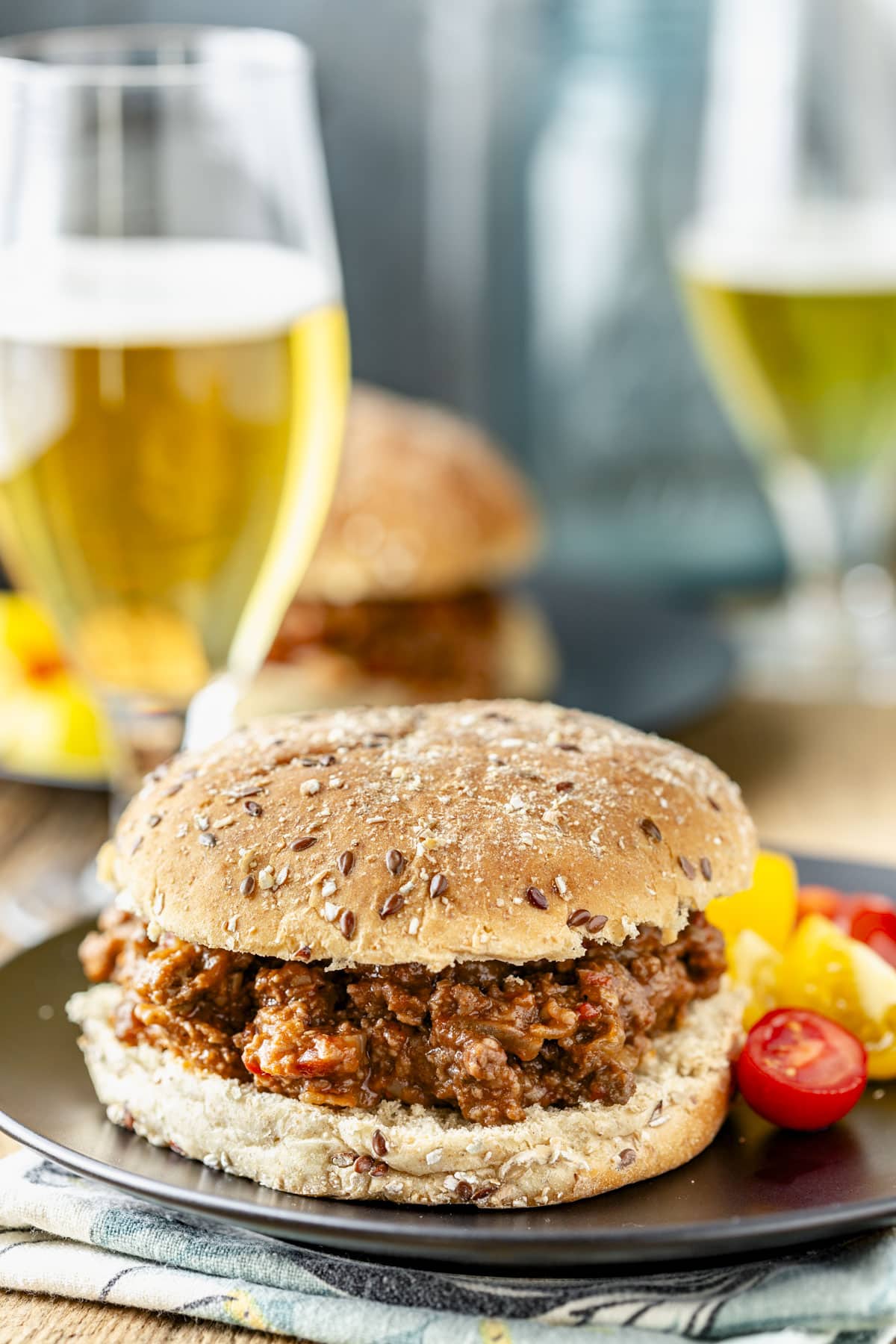 a sloppy joe sandwich on a bun on a black plate