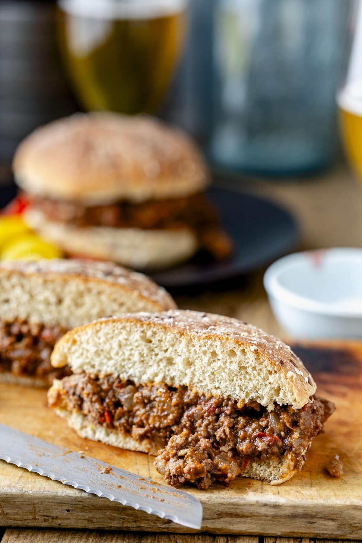 a sloppy joe sandwich cut in half on a cutting board with some of the filling spilling out
