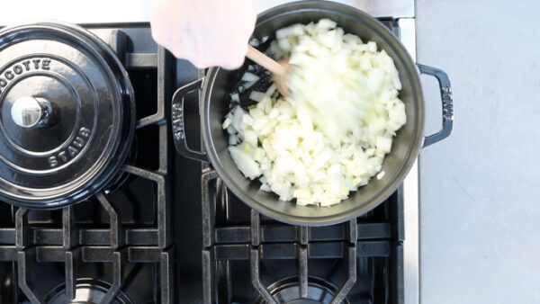 cooking the onion in a Dutch oven with a wooden spoon
