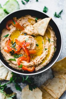 red pepper hummus with a pita chip in it