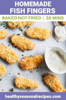 a sheet pan with baked fish fingers on it and a ramequin of tartar sauce
