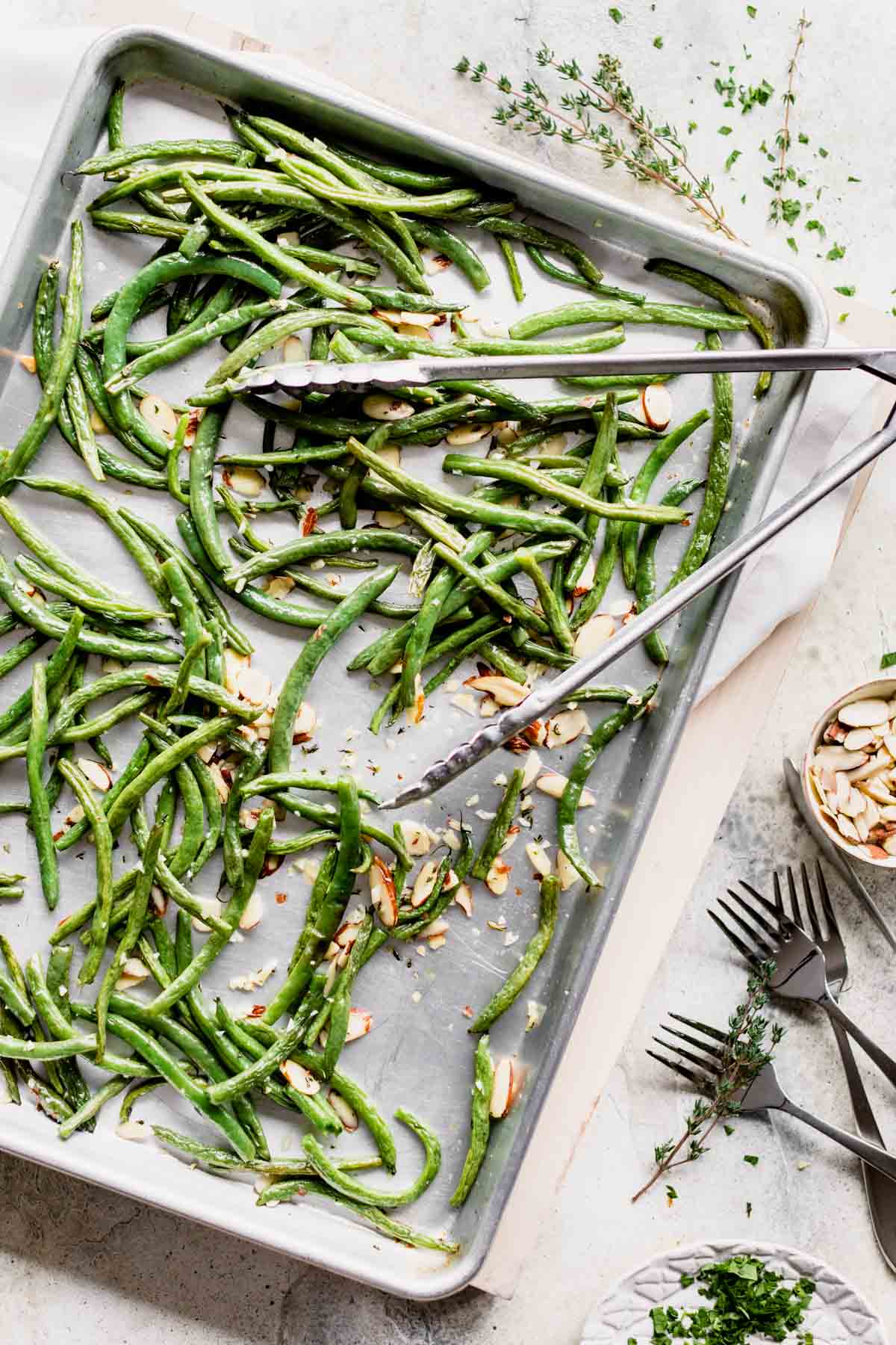 a pan of roasted green beans from overhead with a set of tongs on top