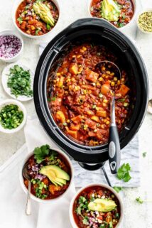 Slow Cooker chili in the slow cooker with bowls of chili on the table