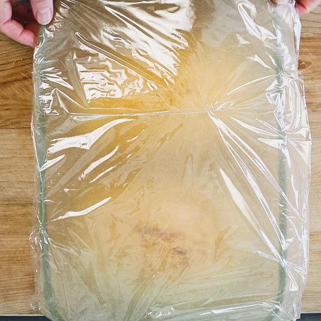 the casserole dish with parchment and plastic covering it