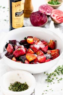 a bowl of beets chunks from the side with a bottle of balsamic vinegar behind it