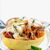 side view of cheesy stuffed spaghetti squash with cheese pull