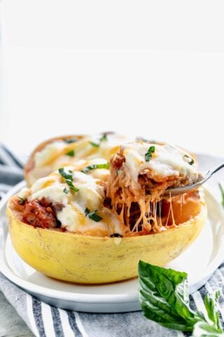 side view of cheesy stuffed spaghetti squash with cheese pull