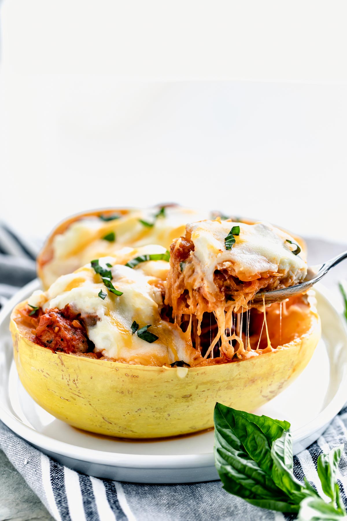 side view of cheesy stuffed spaghetti squash with cheese pull