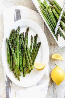 grilled asparagus on a platter with lemons