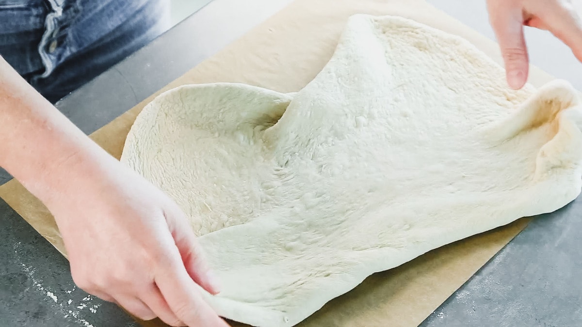 placing the pizza dough on the parchment