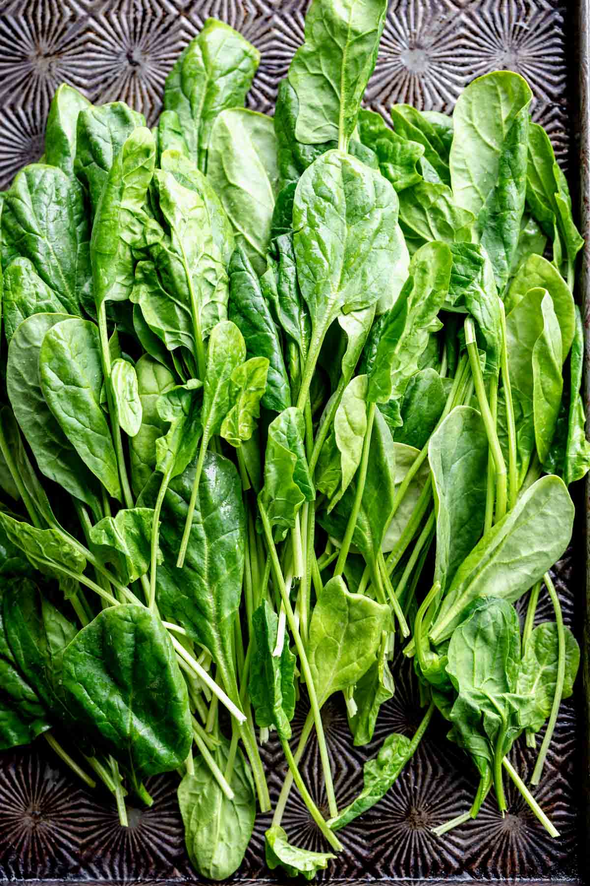 A bunch of spinach leaves on a dark table.