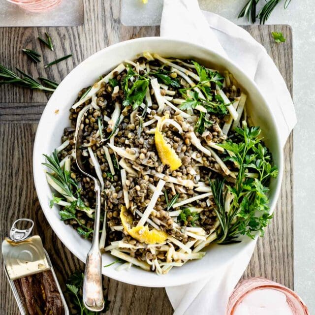 lentil and celery root salad with herbs in a bowl from overhead with pink water glasses
