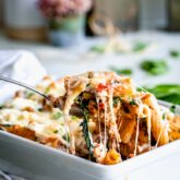 a scoop of cheesy pasta bake with cheese pull