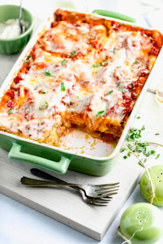 the squash lasagna in a green casserole dish on a white cutting board