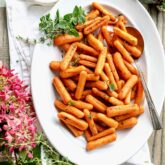 an oval platter with roasted baby carrots on it