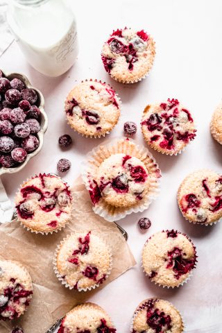 Cranberry orange muffins on parchment paper on counter, sugared cranberries in a bowl