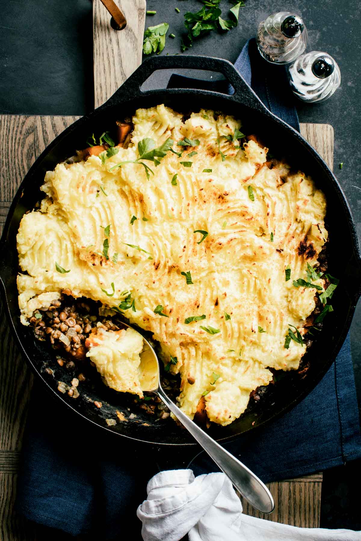 overhead photo of vegetarian shepherd's pie in cast iron skillet with scoop of pie in a spoon